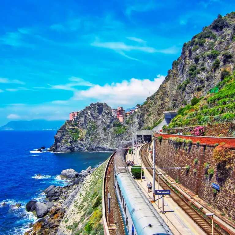 Train longeant la côte des Cinque Terre entre falaises et mer Méditerranée.
