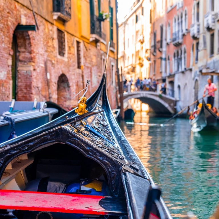 Gondole traditionnelle naviguant sur un petit canal bordé de façades colorées à Venise