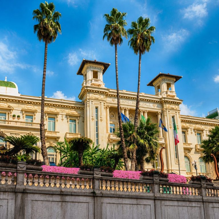 Façade du Casino municipal de Sanremo entourée de palmiers.