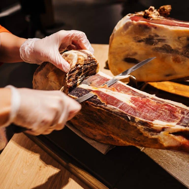Découpe d’un jambon italien affiné dans une épicerie traditionnelle.