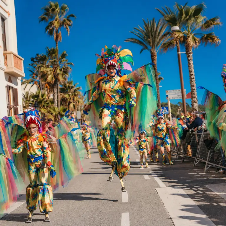Échassiers en costumes multicolores défilant pendant le Carnaval de Lloret de Mar.